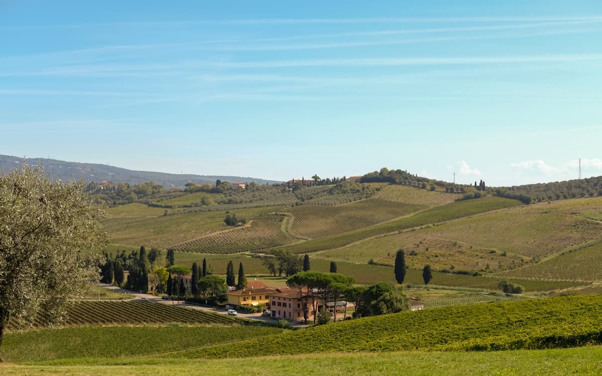 Rolling Tuscan hills with vineyards and a villa